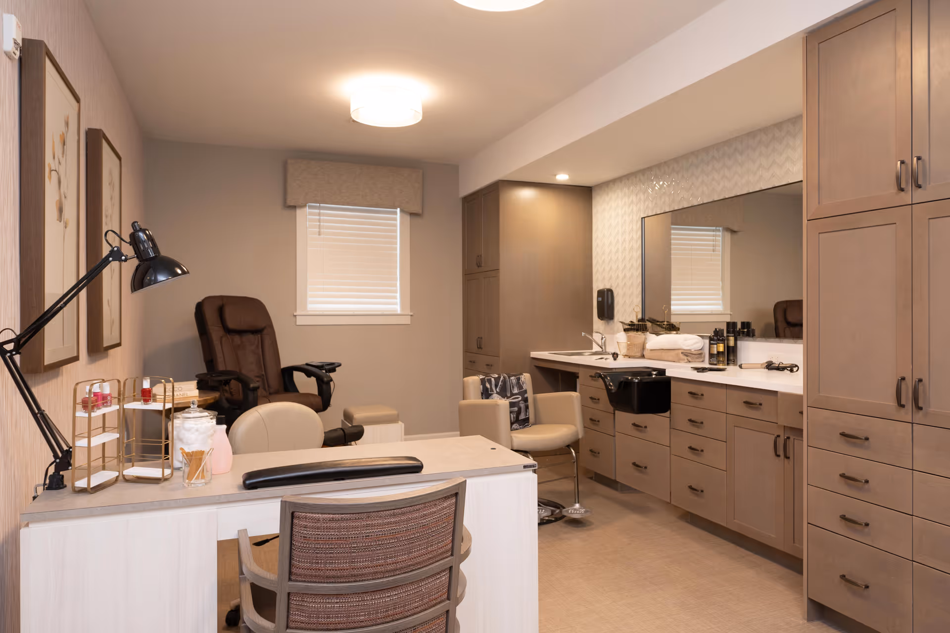 Well-lit interior salon room with manicure/pedicure stations, reclining chairs, a sink, and built-in cabinetry.
