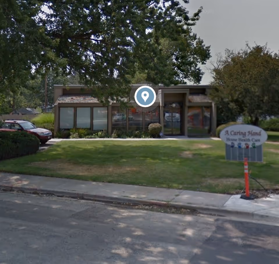 Exterior view of a single-story facility with a sign reading A Caring Hand Home Health Care.