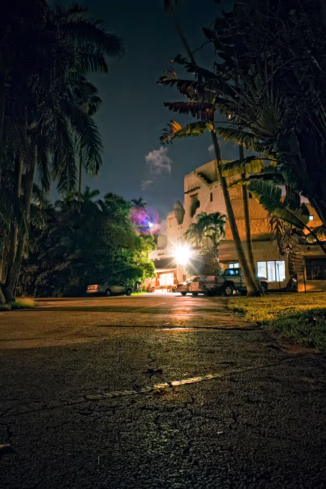 Night exterior view of Fair Havens Center with illuminated entrance and palm trees along a driveway.
