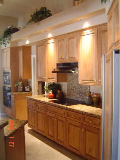 Wooden kitchen cabinets line granite counters with appliances in a bright indoor kitchen.