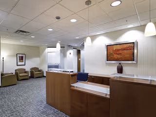 Reception area of a senior living facility lobby with wood desks, seating, and artwork.