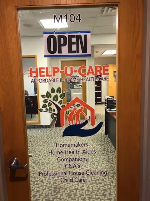 Door with OPEN sign and Help-U-Care logo; office interior visible beyond.