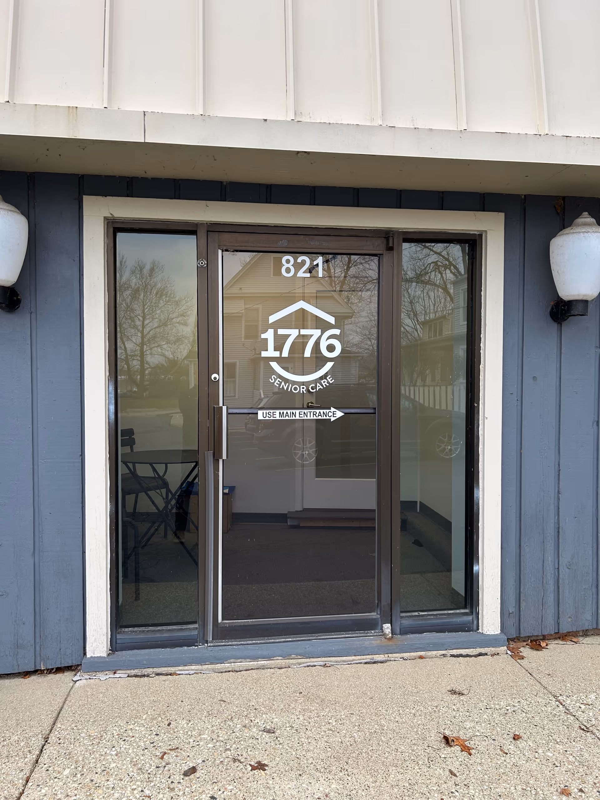 Glass front entrance of 1776 Senior Care with 'Use Main Entrance' sign.