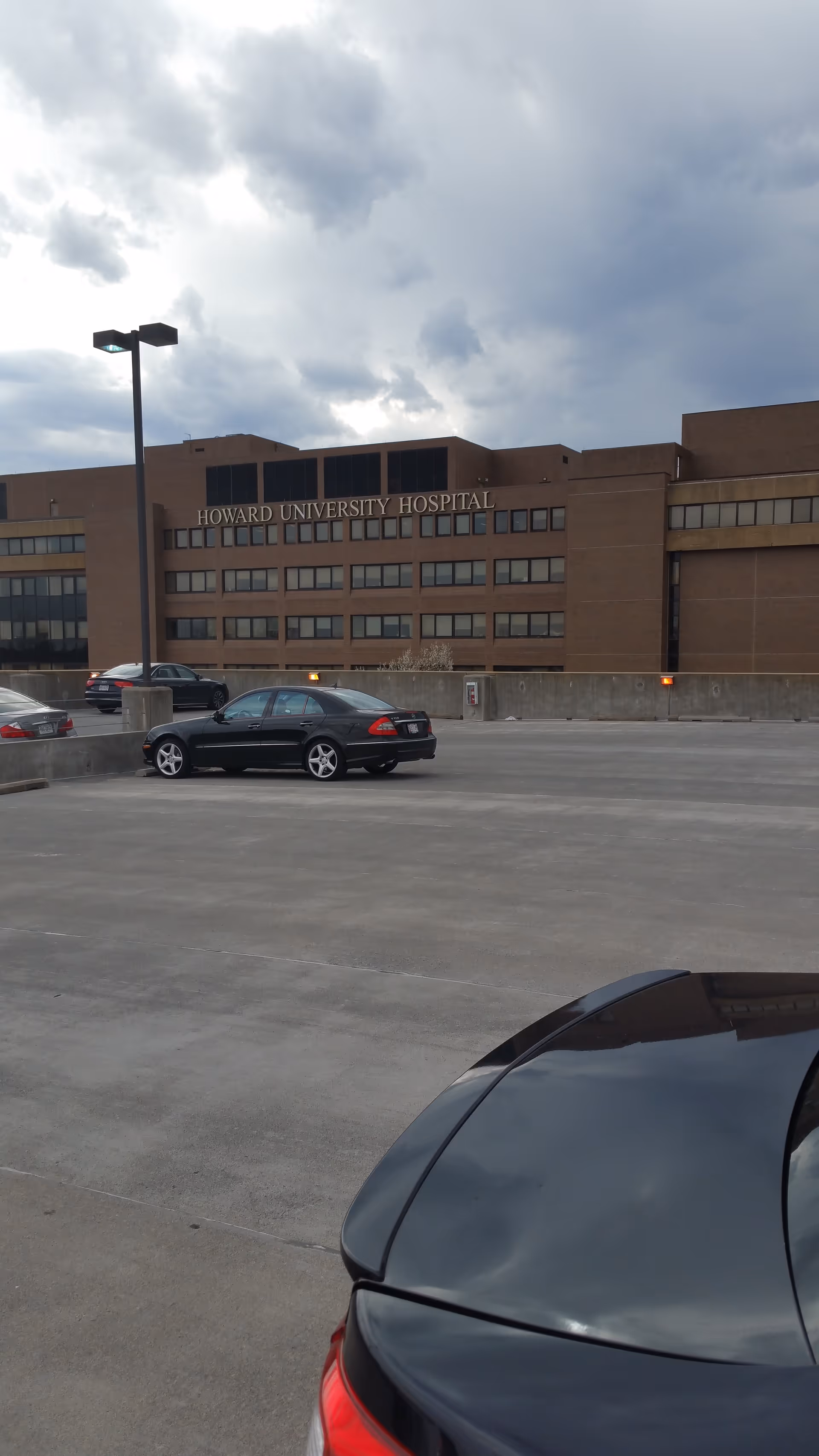 Exterior view of Howard University Hospital with cars in the parking lot.