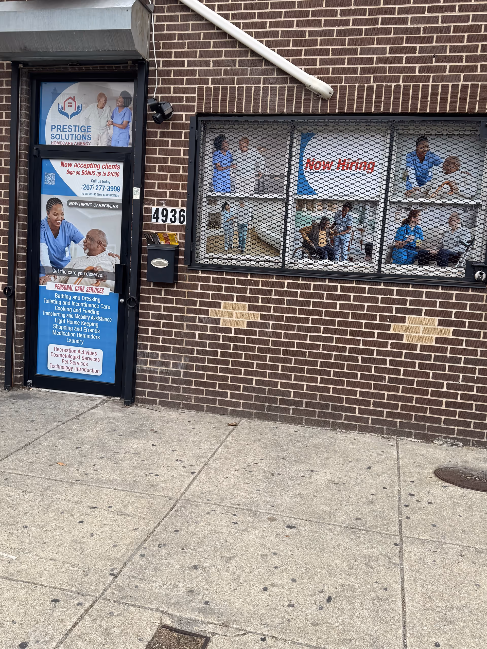 Brick storefront for Prestige Solutions HomeCare Agency with posters and Now Hiring sign.