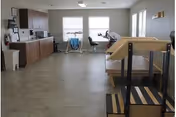 Spacious interior common area with kitchenette, seating by windows, and a wooden multi-step platform.