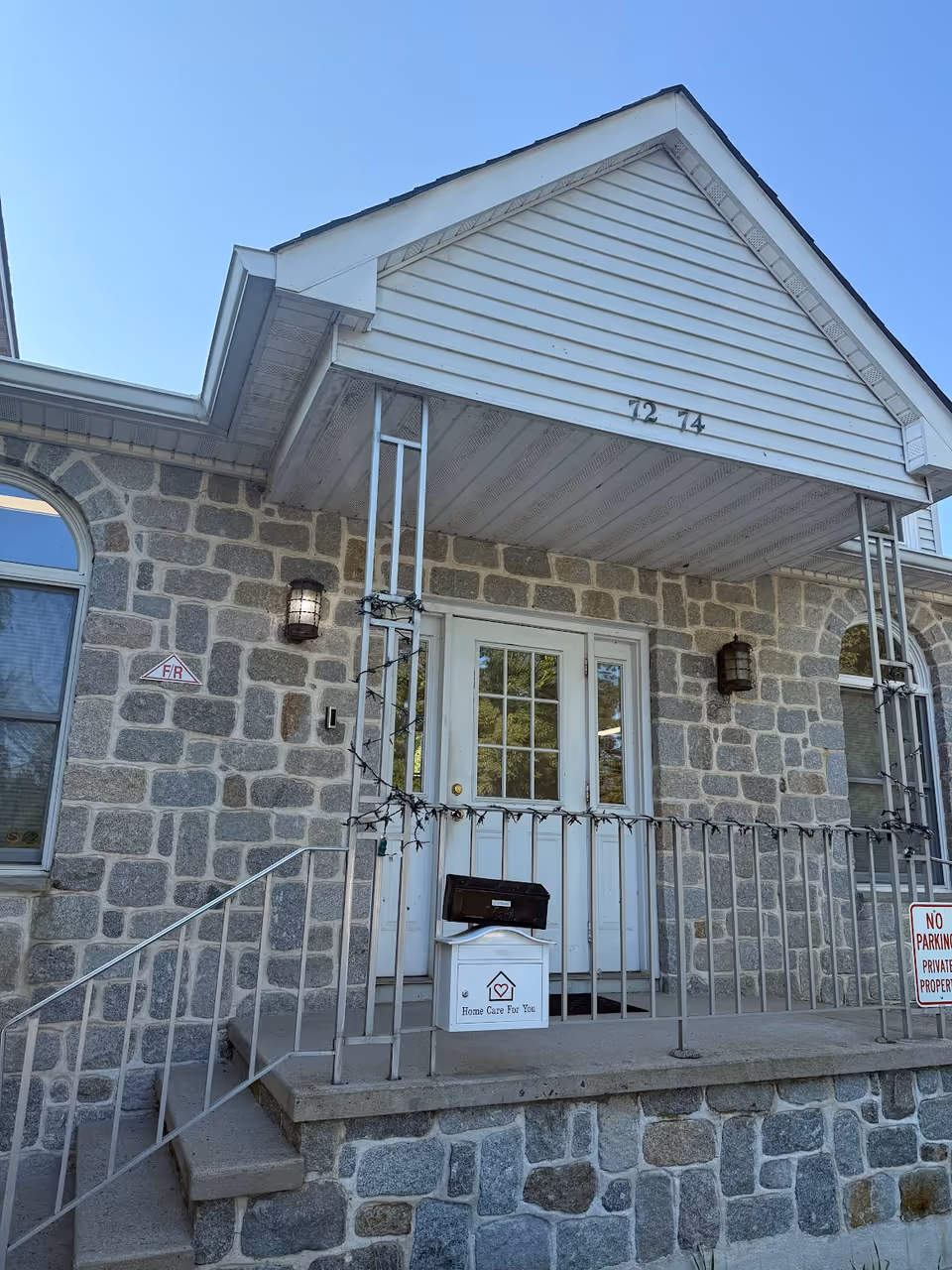 Stone building front with porch, stairs, railings, and Home Care For You mailbox.
