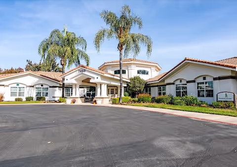 Front view of Lakeside Landings senior living facility with palm trees and a parking area.
