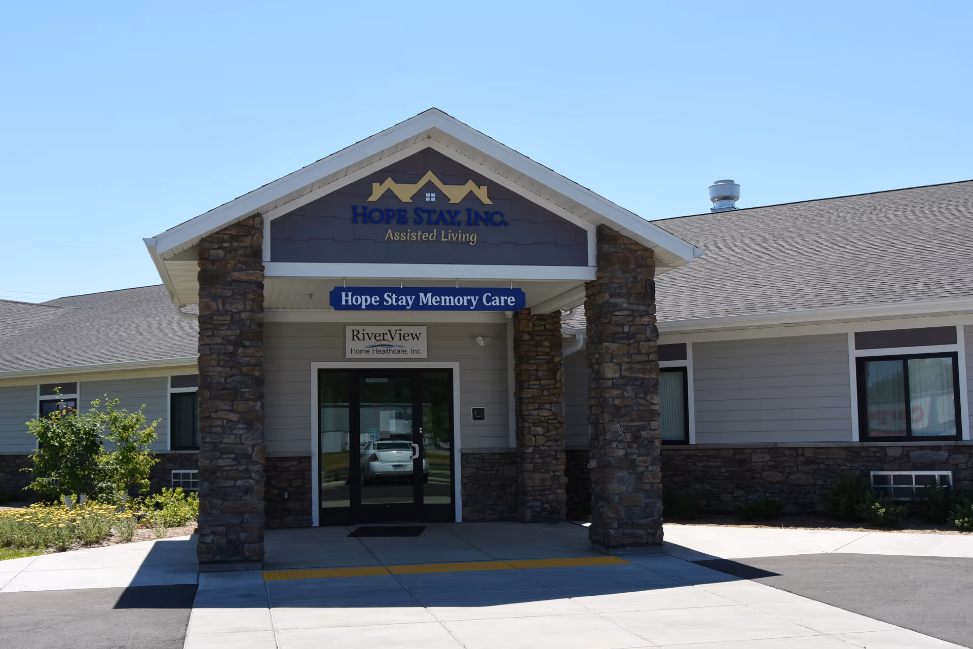 Entrance of Hope Stay Memory Care facility with stone pillars and a blue sign.