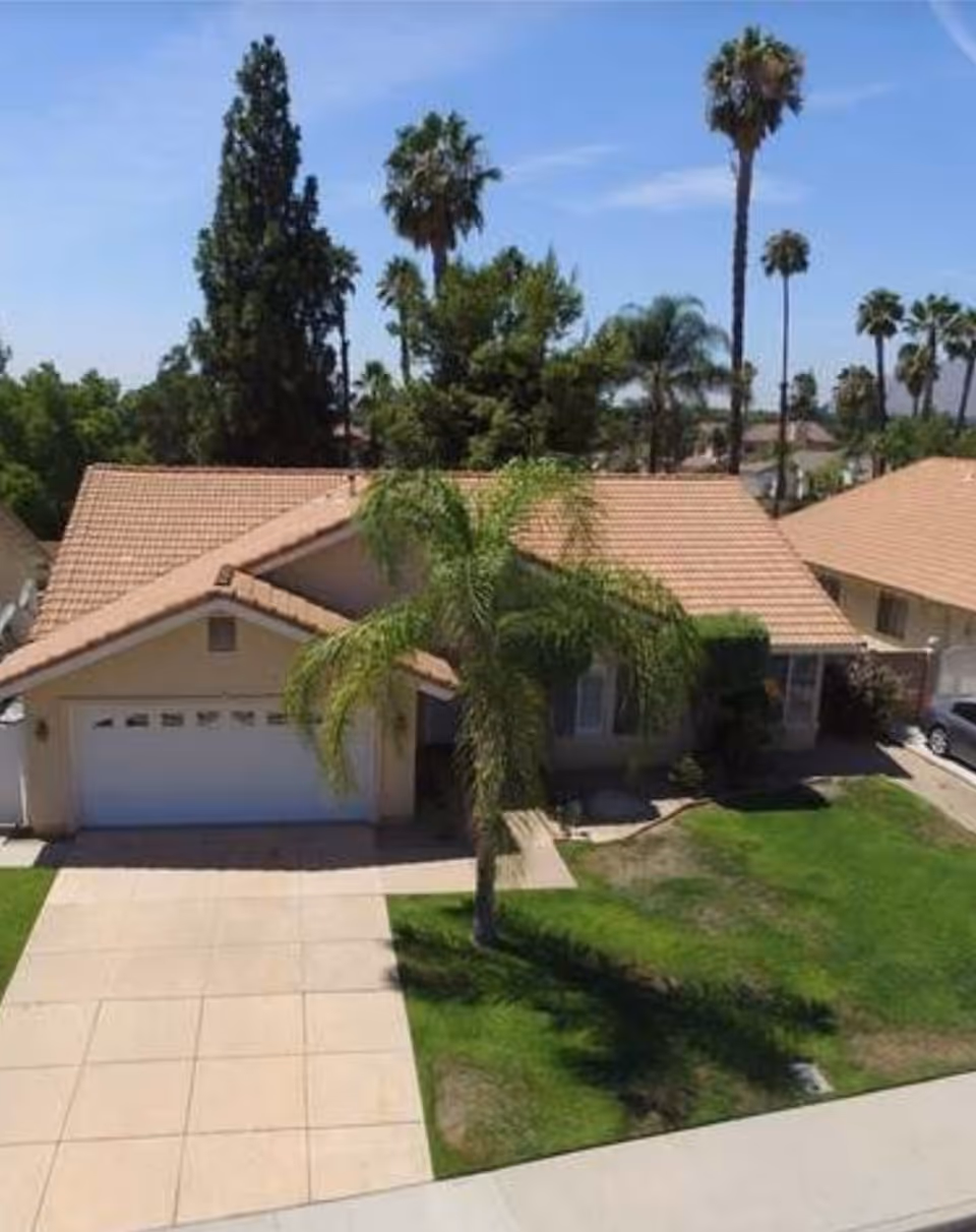 Front view of a beige, single-story home with palm trees and a tiled roof.
