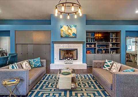 Blue-walled resident lounge with two sofas, a fireplace, artwork, and built-in shelves.