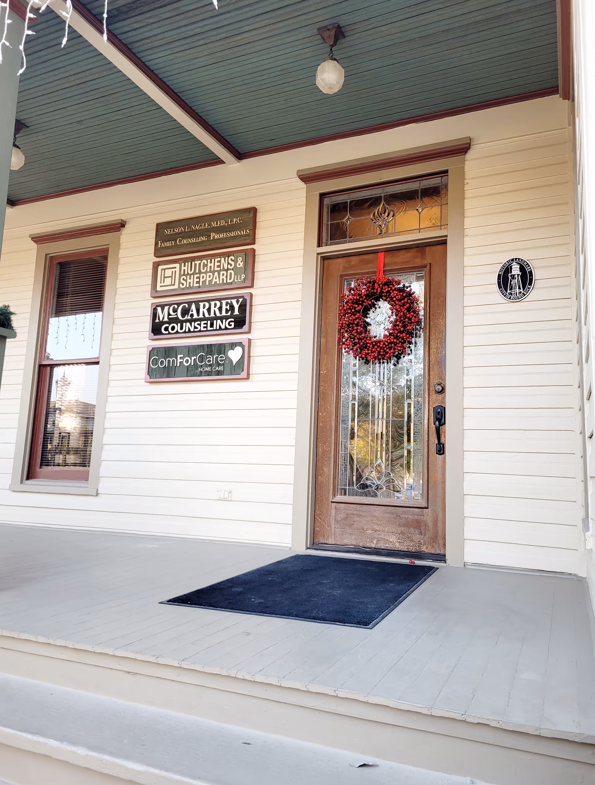 Front entrance of a building with multiple business signs and a wreath on the door.