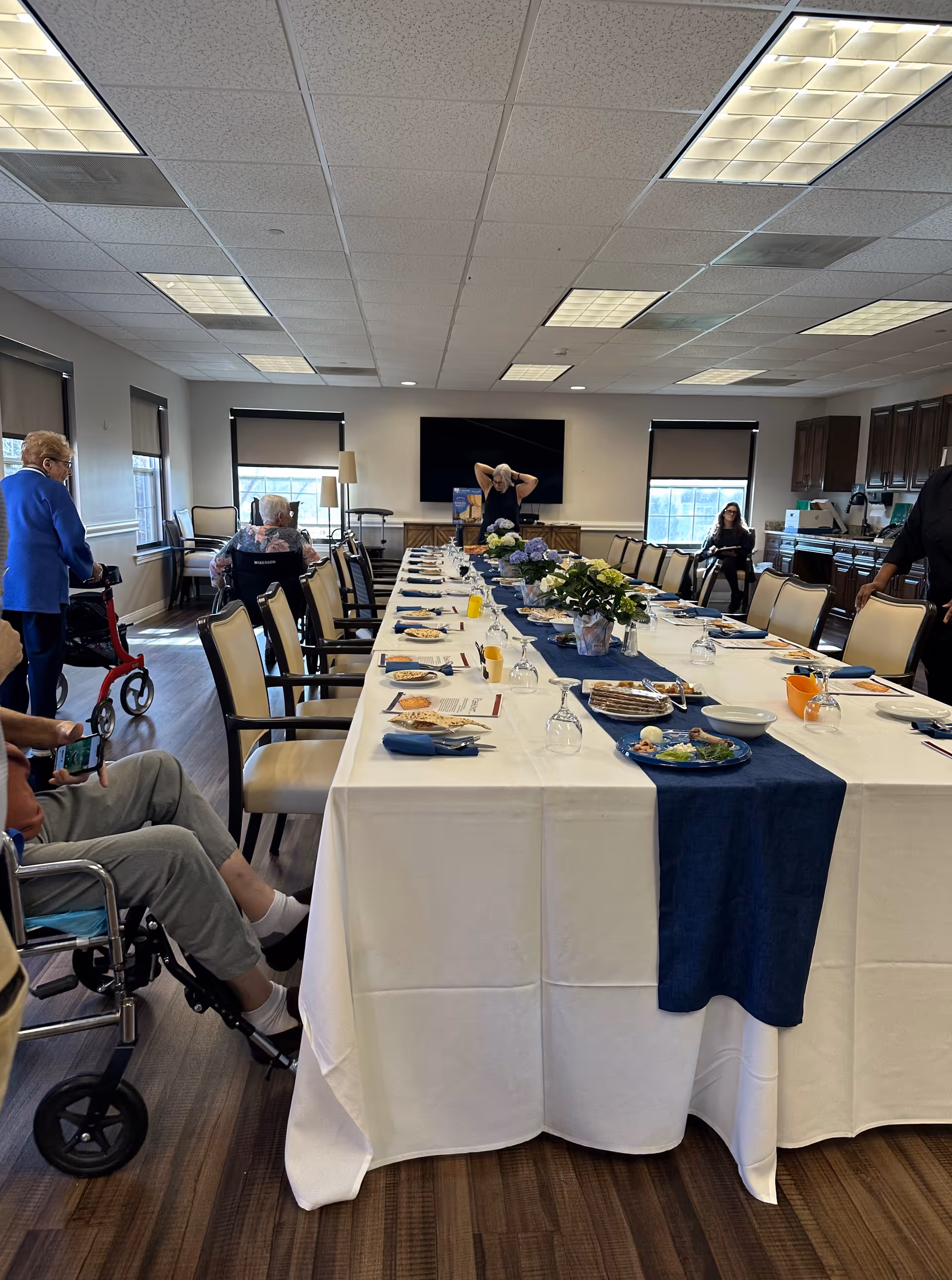 A long dining table set for a group meal in Belmont Village senior living dining room.