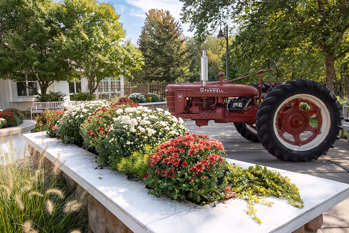 Red vintage tractor sits beside a flower-filled planter outside the facility.