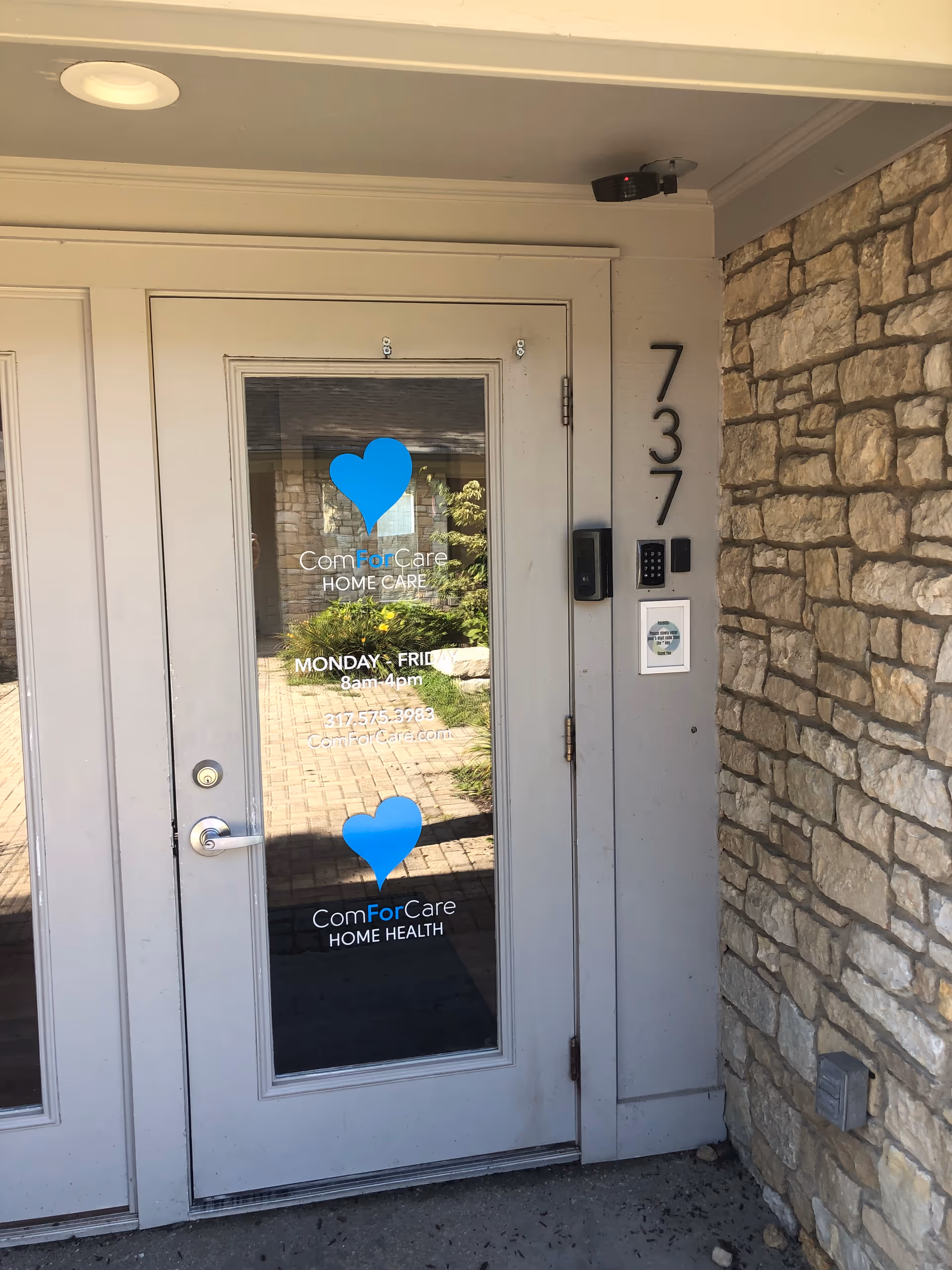 Front entrance of ComForCare Home Care building with glass door and stone exterior.