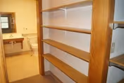 Wooden built-in shelves line a hallway, with a bathroom visible through an open door.