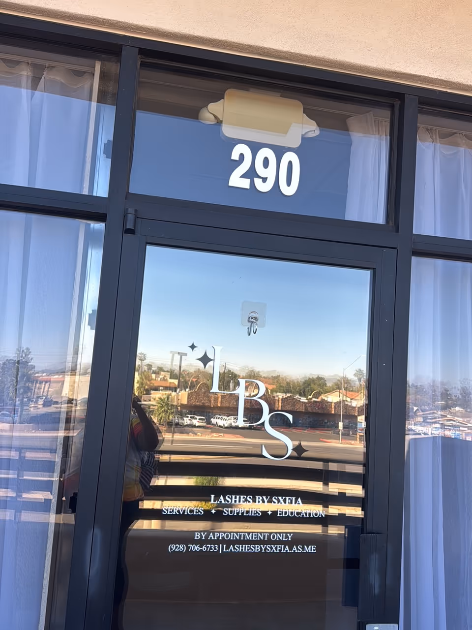 Glass storefront door with the number 290 and LBS signage reflecting the street.