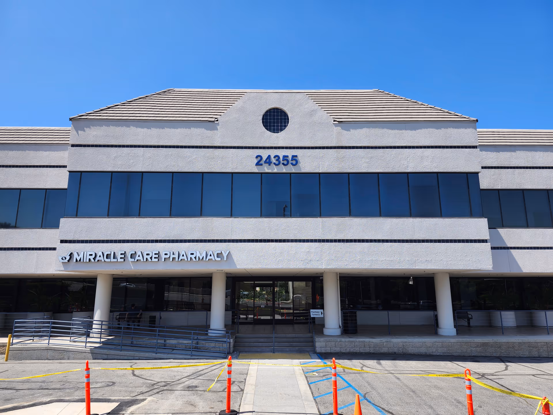 Two-story medical building with Miracle Care Pharmacy storefront and blue-tinted windows.