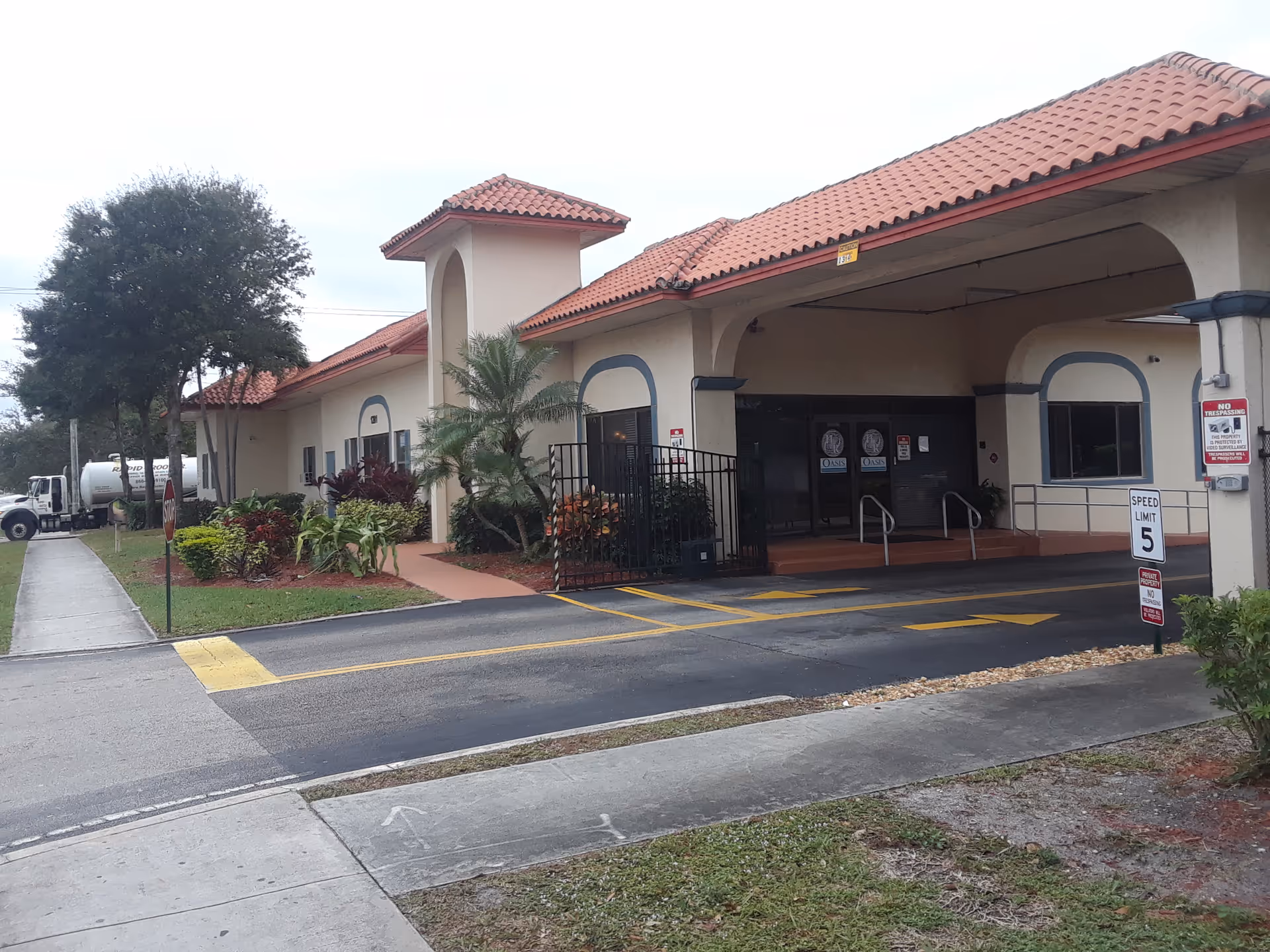 Exterior view of Lake Worth Rehabilitation Center entrance with arches and red-tile roof