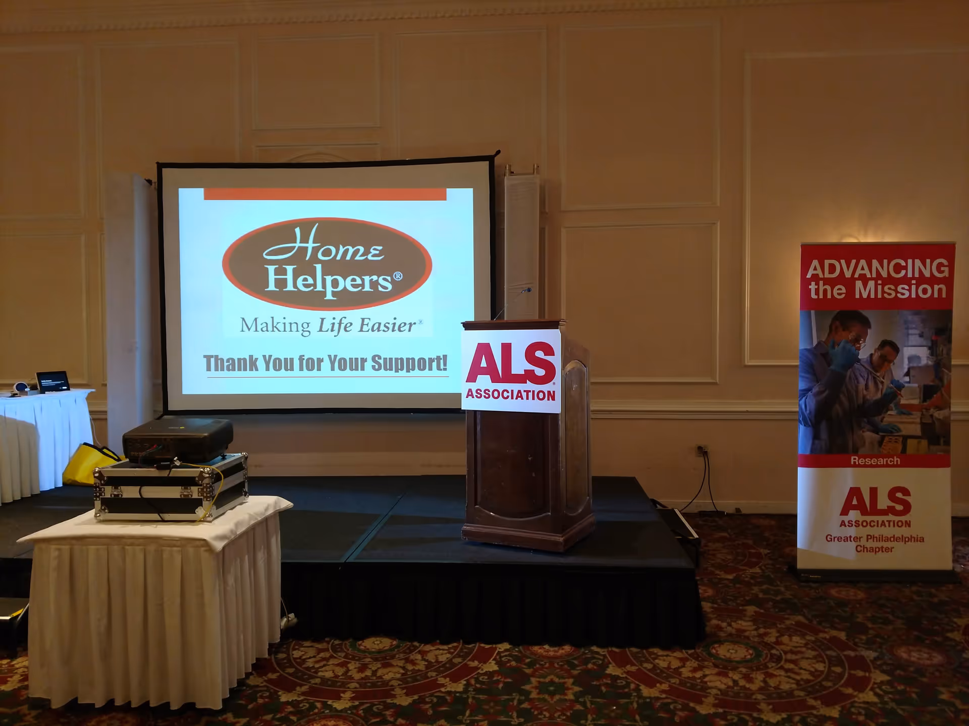 Conference room setup with projector screen displaying Home Helpers logo and ALS banner.