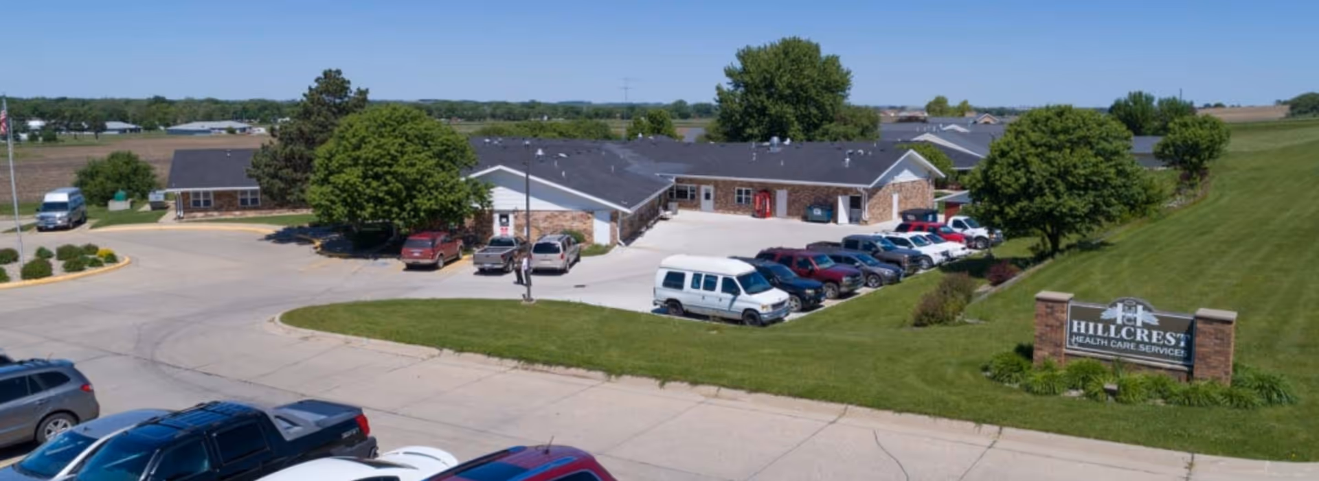 Exterior view of a low, brick senior living facility with a parking lot.