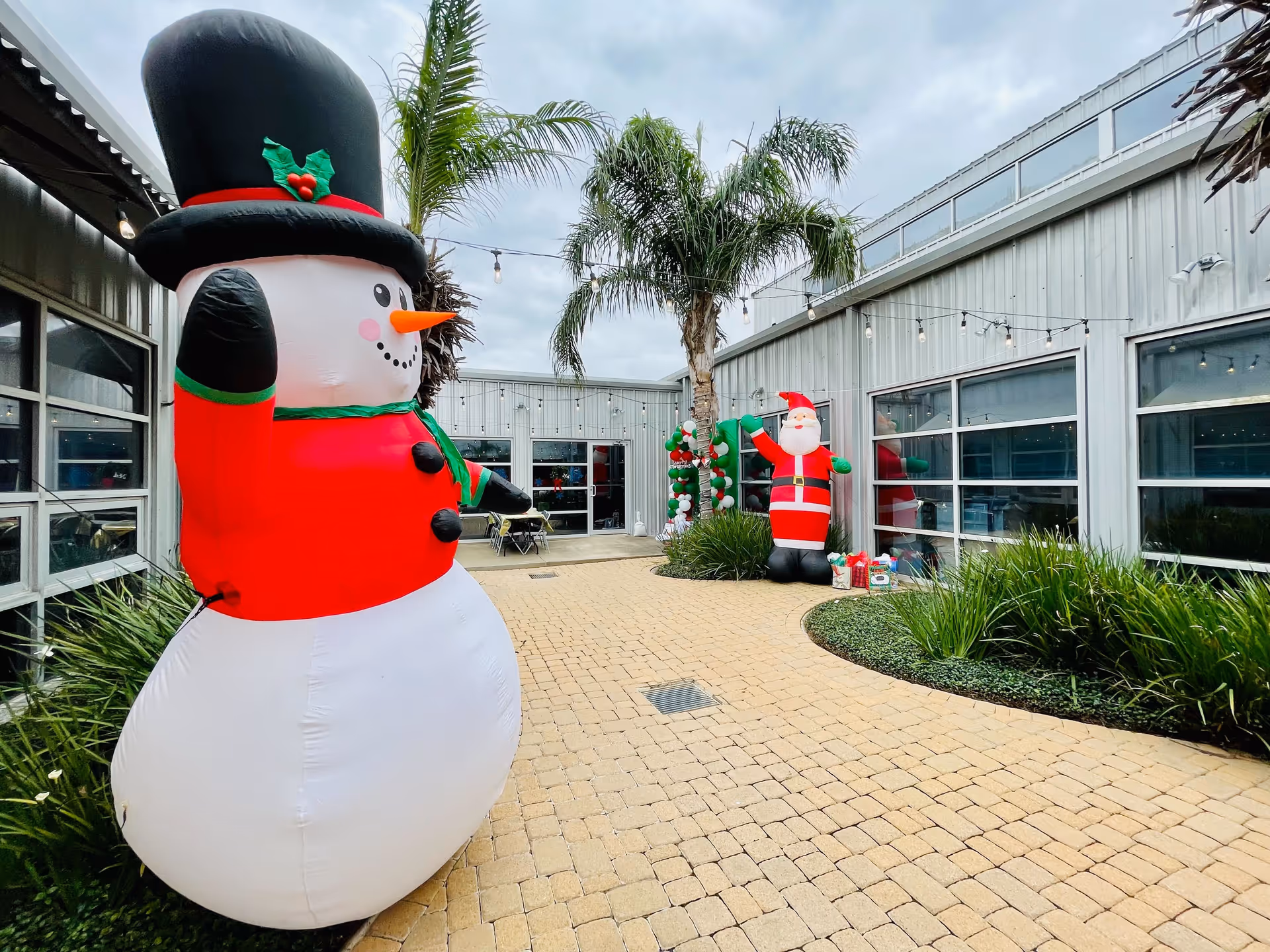Outdoor courtyard with large inflatable snowman and Santa decorations.