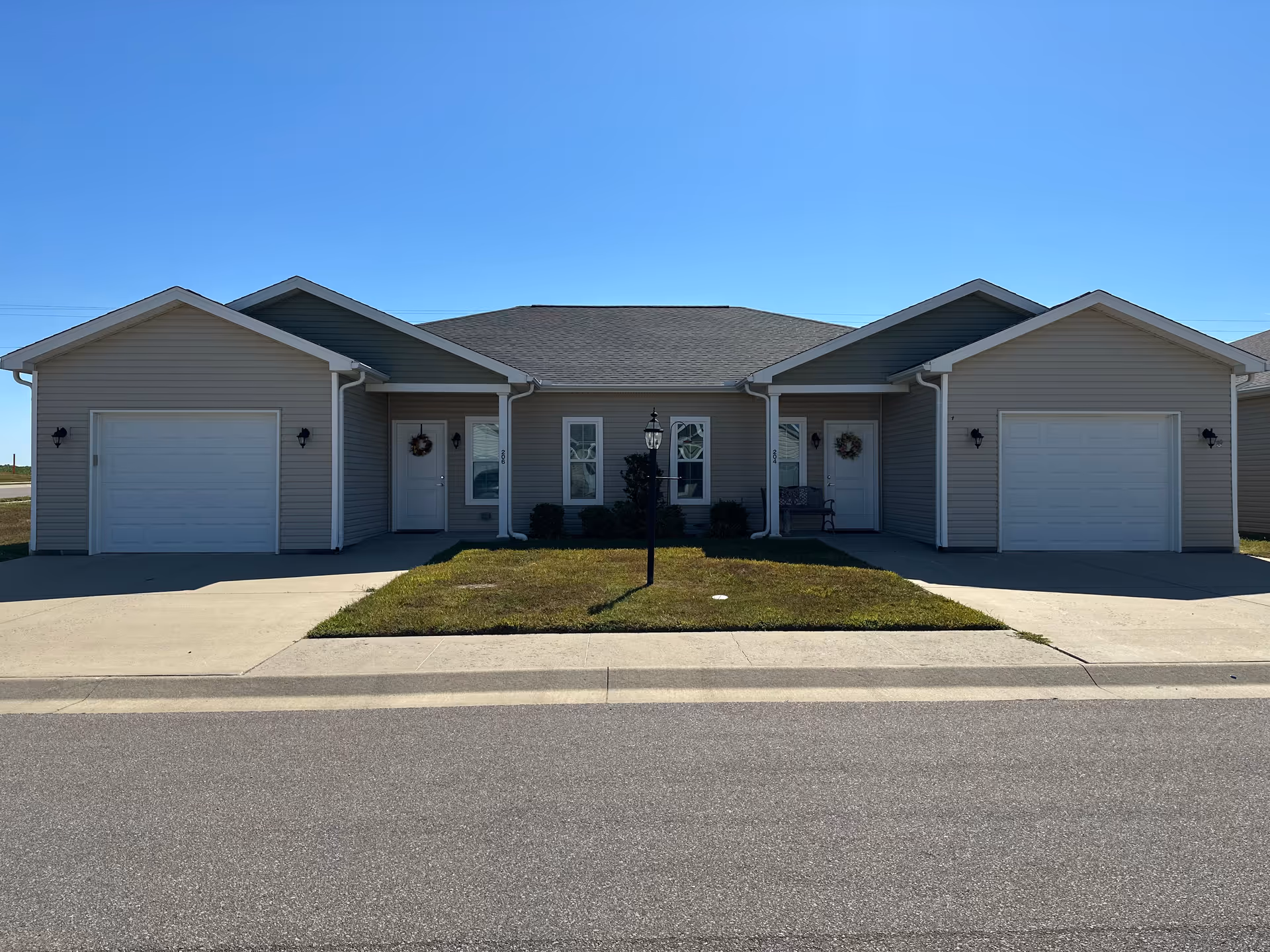 Front exterior of a single-story senior living building with multiple entrances and garages.