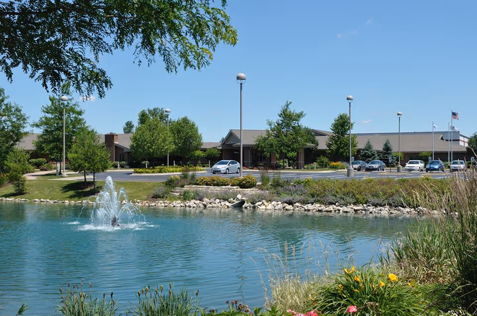 Exterior view of Lightways hospice facility beside a pond with a fountain.