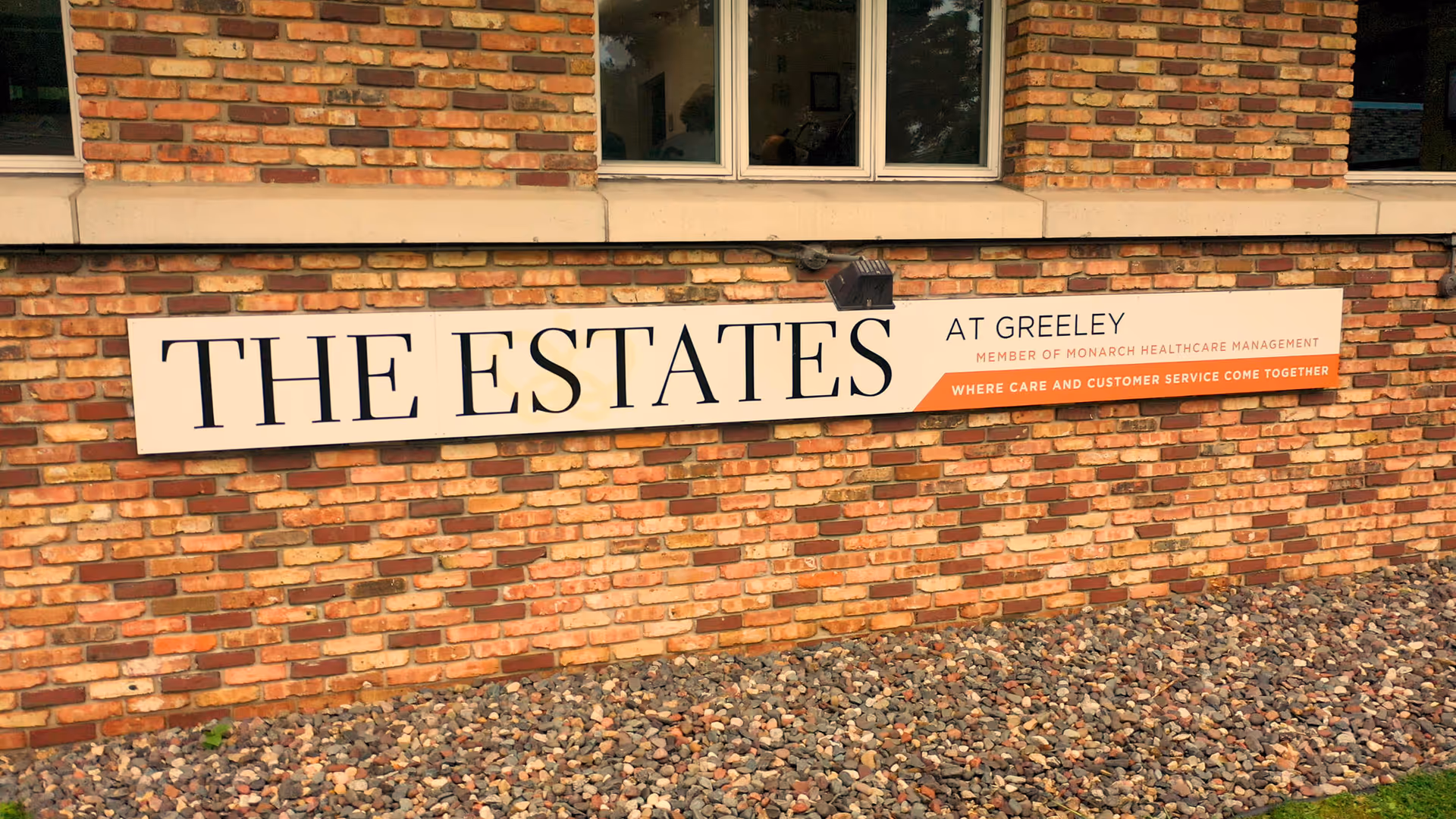 Brick exterior wall features a large sign reading THE ESTATES at Greeley.