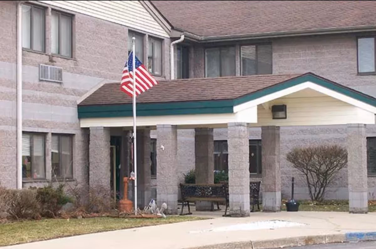 Exterior view of Wood Ridge Assisted Living entrance with flagpole and seating area.