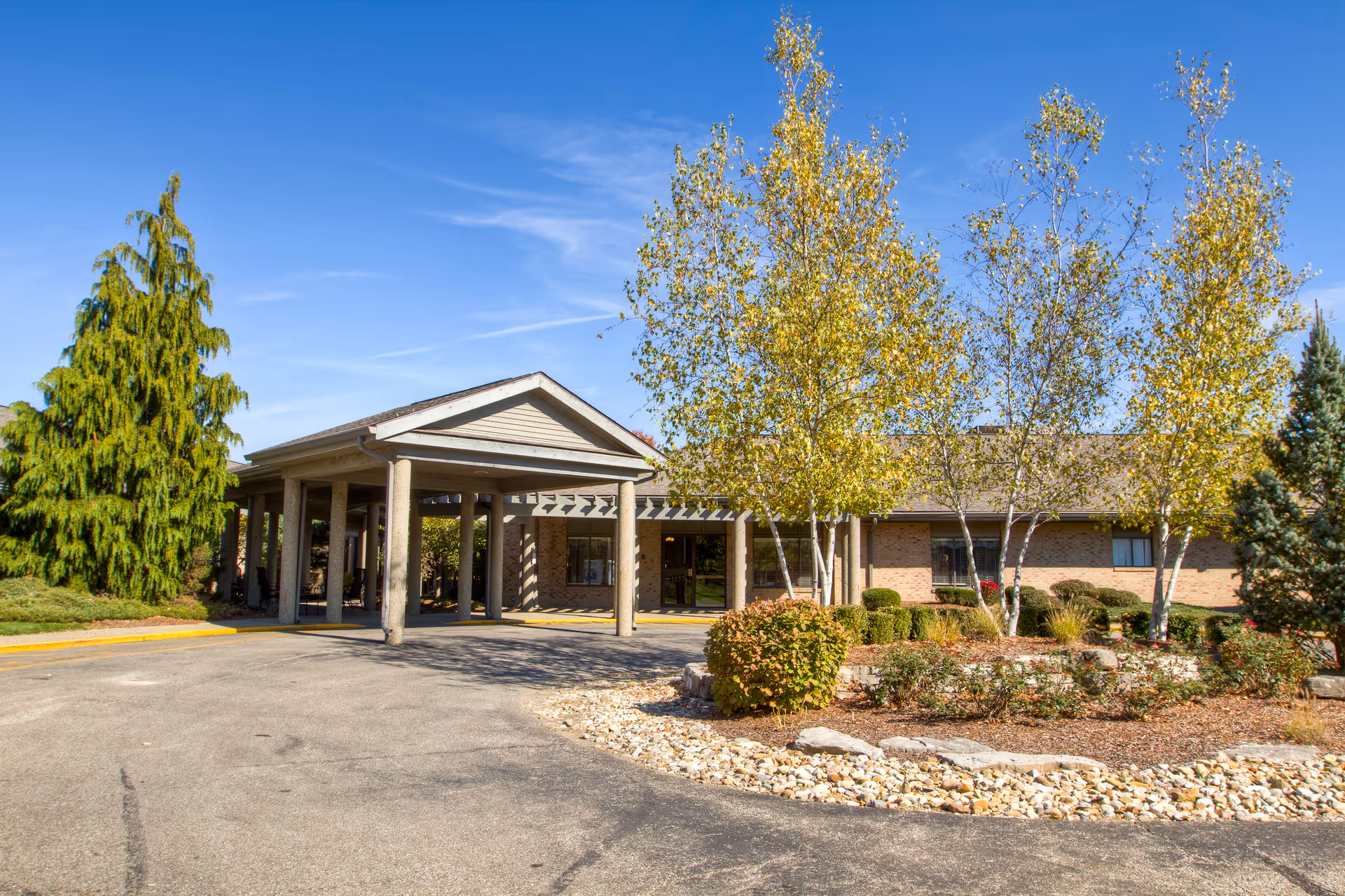 Brick senior living facility with a covered entrance and landscaped front yard.