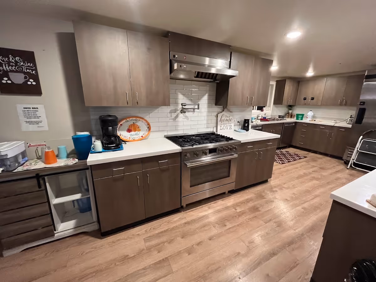 Modern communal kitchen with stainless steel stove, cabinetry, and counters in a senior facility.