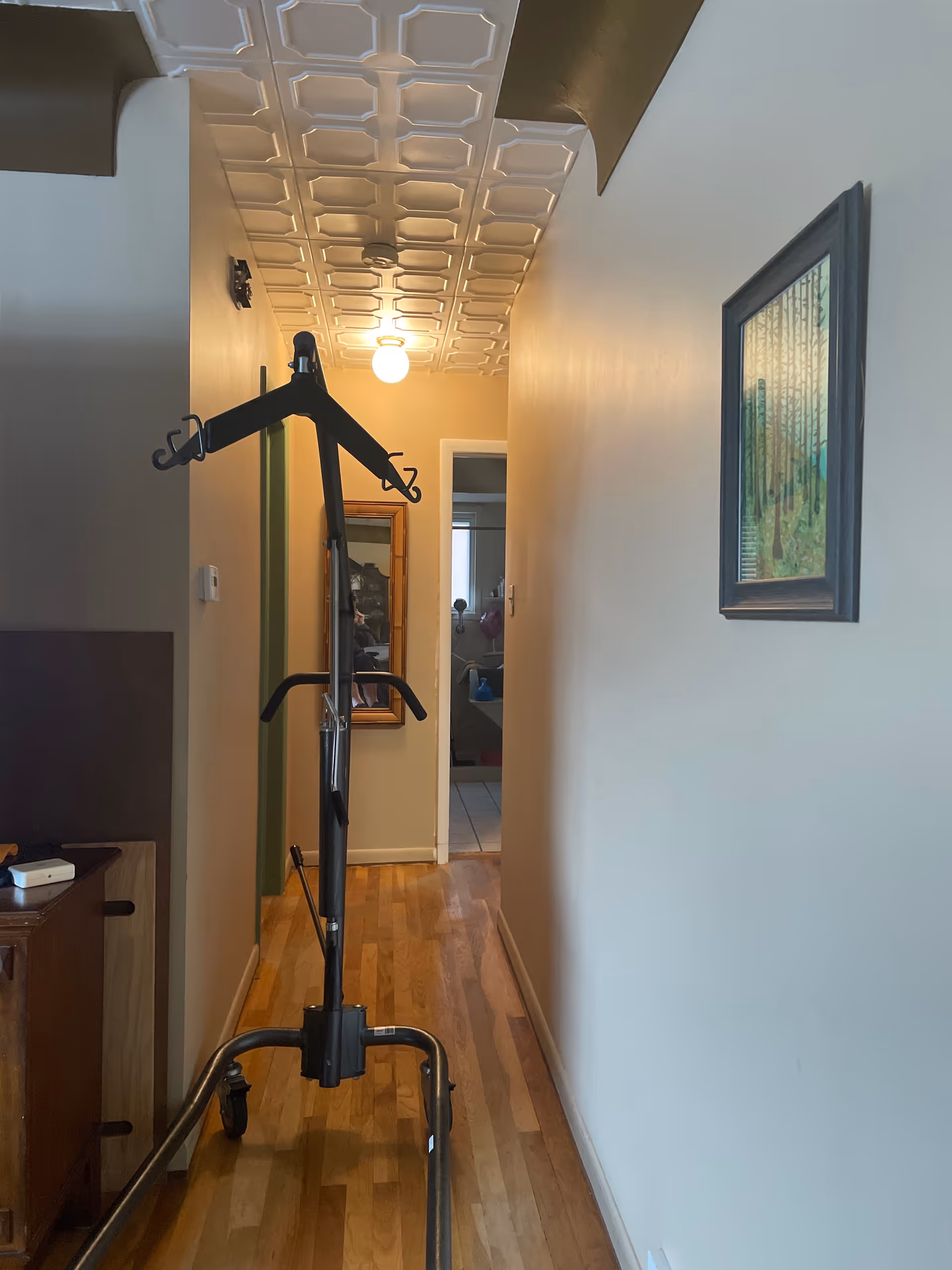 Narrow hallway in Hart Medical Equipment facility with a standing exercise frame and wall art.