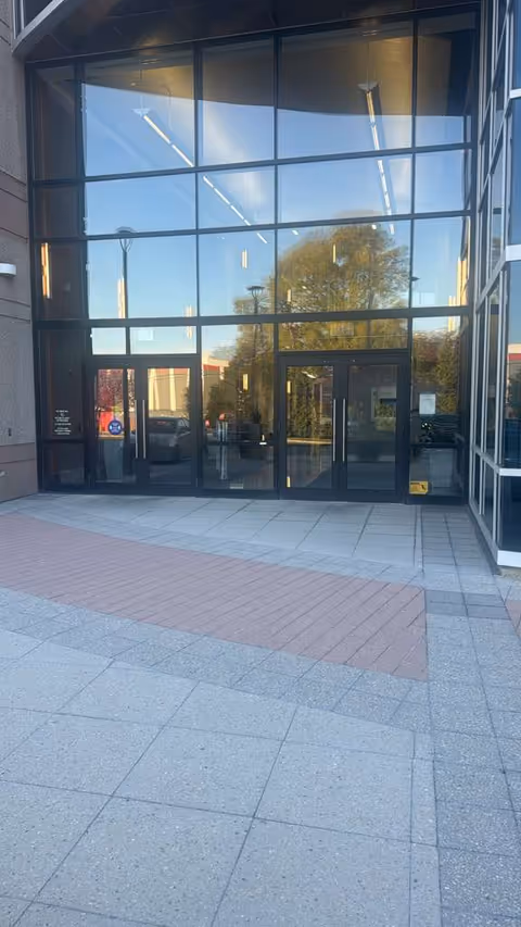 Front entrance of a modern building with large glass windows and doors.
