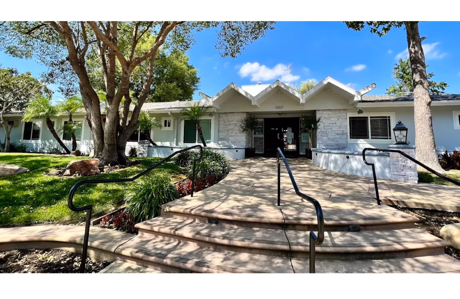 Front entrance of West Valley Post Acute with stairs, ramp, and landscaped path.