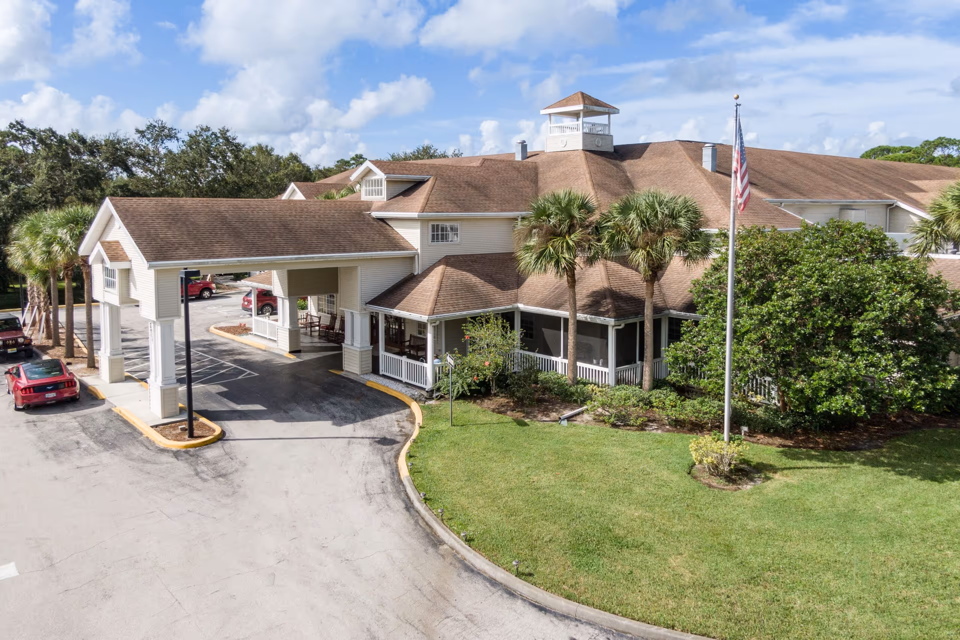 Concordis Senior Living exterior: a large building with a driveway, covered entrance, and palm trees.