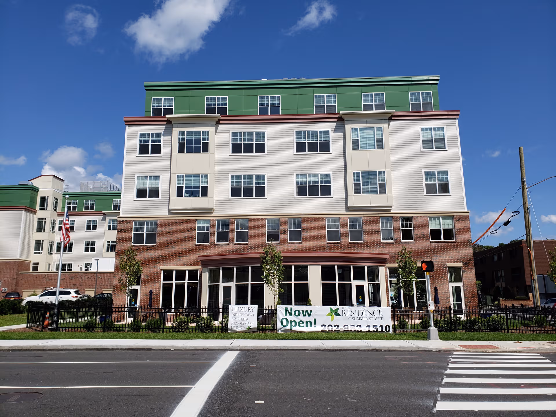 Exterior view of The Residence at Summer Street, a multi-story senior living building with banners.