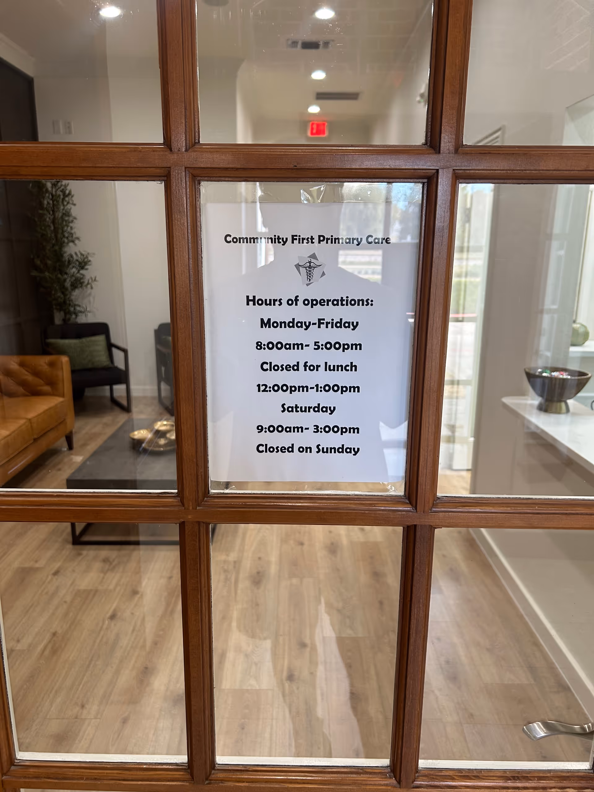 Glass door with posted hours sign for Community First Primary Care in lobby