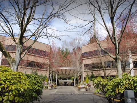 Outdoor view of a senior living campus with tree-lined walkway and brick buildings.
