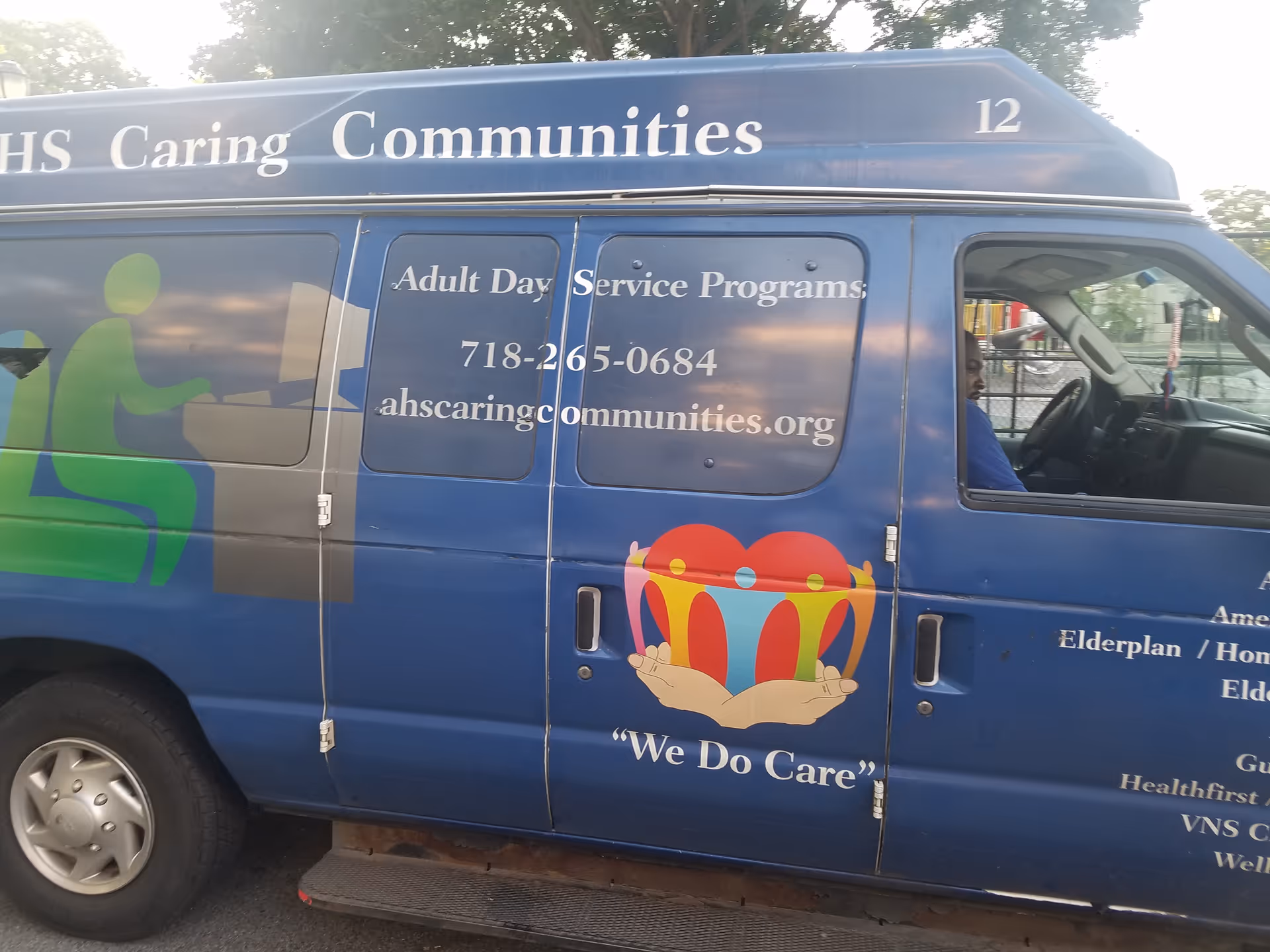 Blue van with Caring Communities signage and logo for Adult Day Service Programs, driver visible.