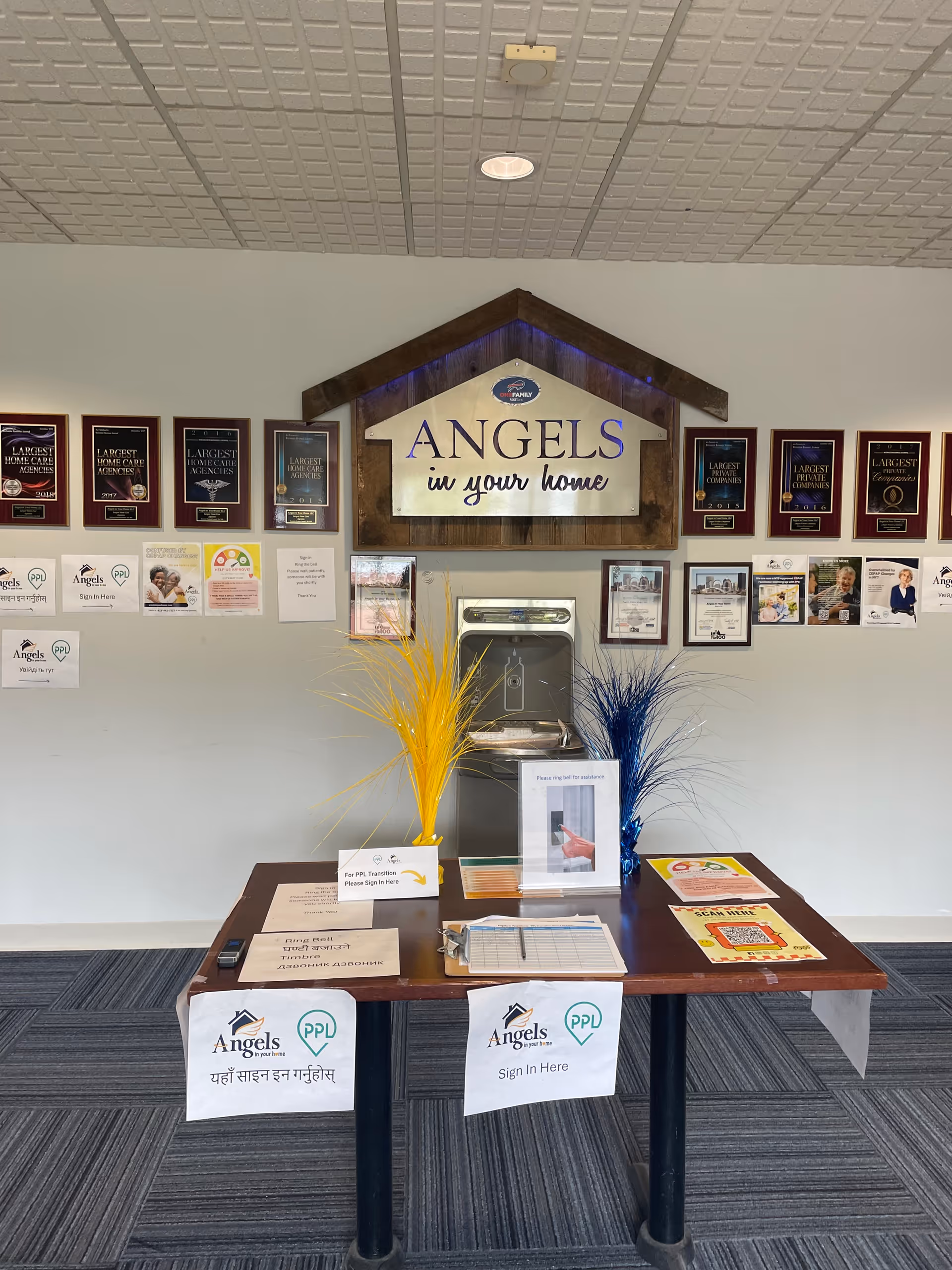 Reception area featuring Angels in Your Home sign, awards, a desk, and decorative grasses.