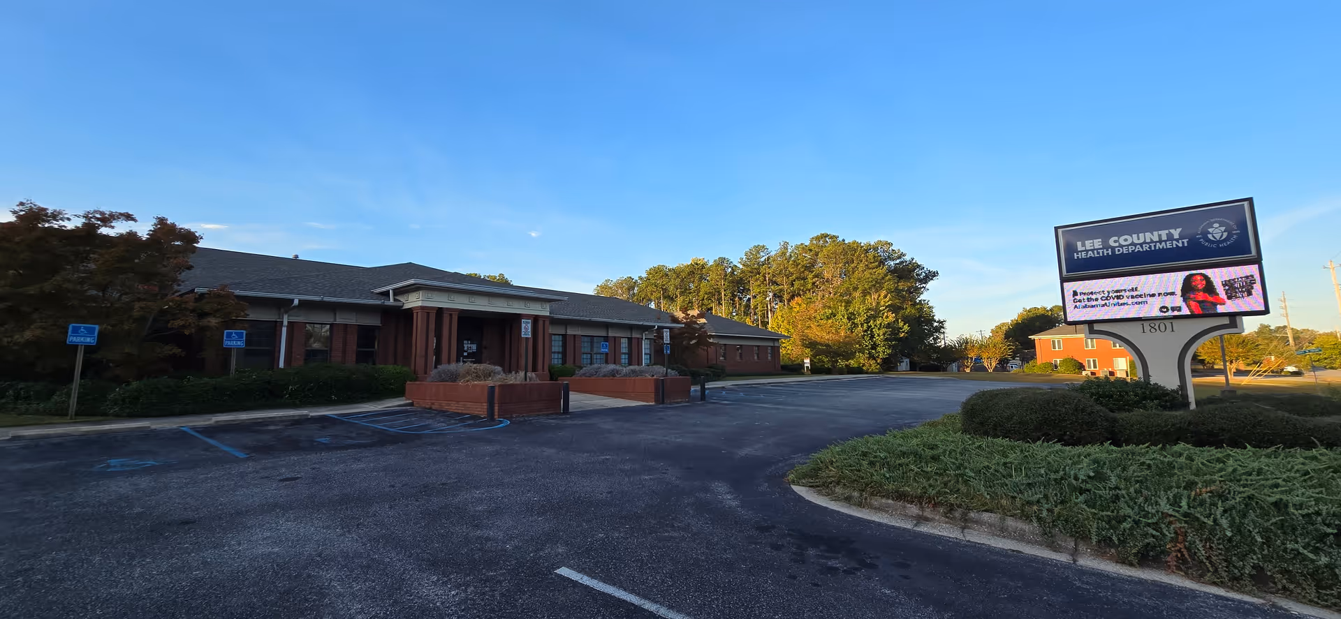Exterior view of a Lee County Health Department building with a parking lot and sign.