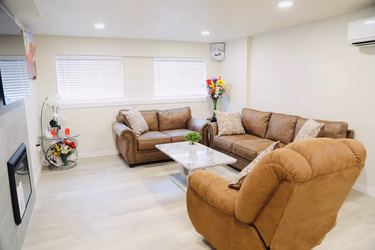 Bright lounge with beige couches, a marble coffee table, and floral decor.
