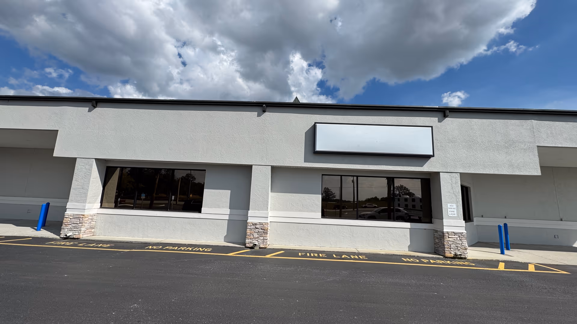 Exterior view of Cornerstone Hospice building with large windows, blank sign, and paved parking lot.