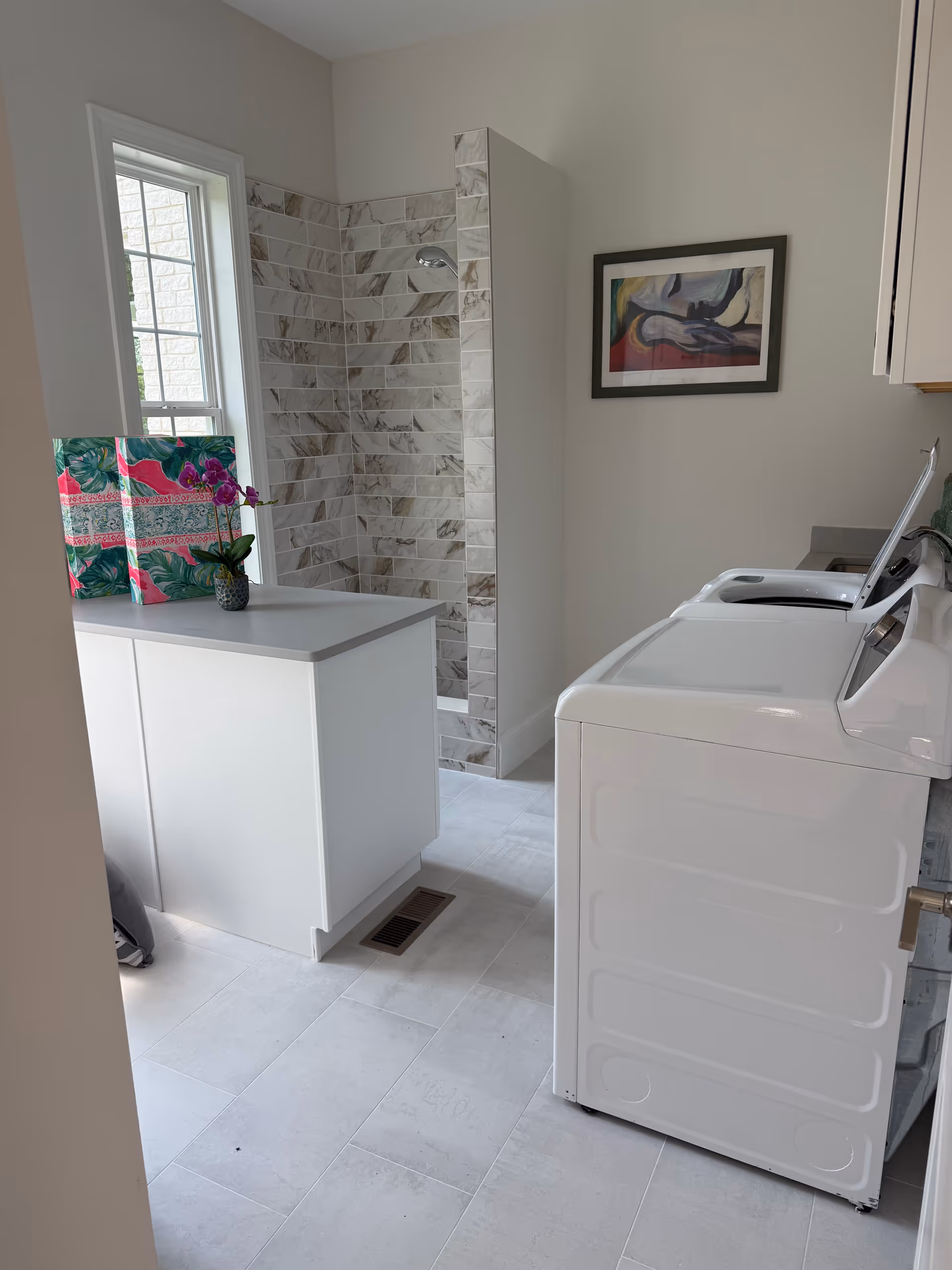 Small laundry area with a washer and dryer beside a tiled shower.