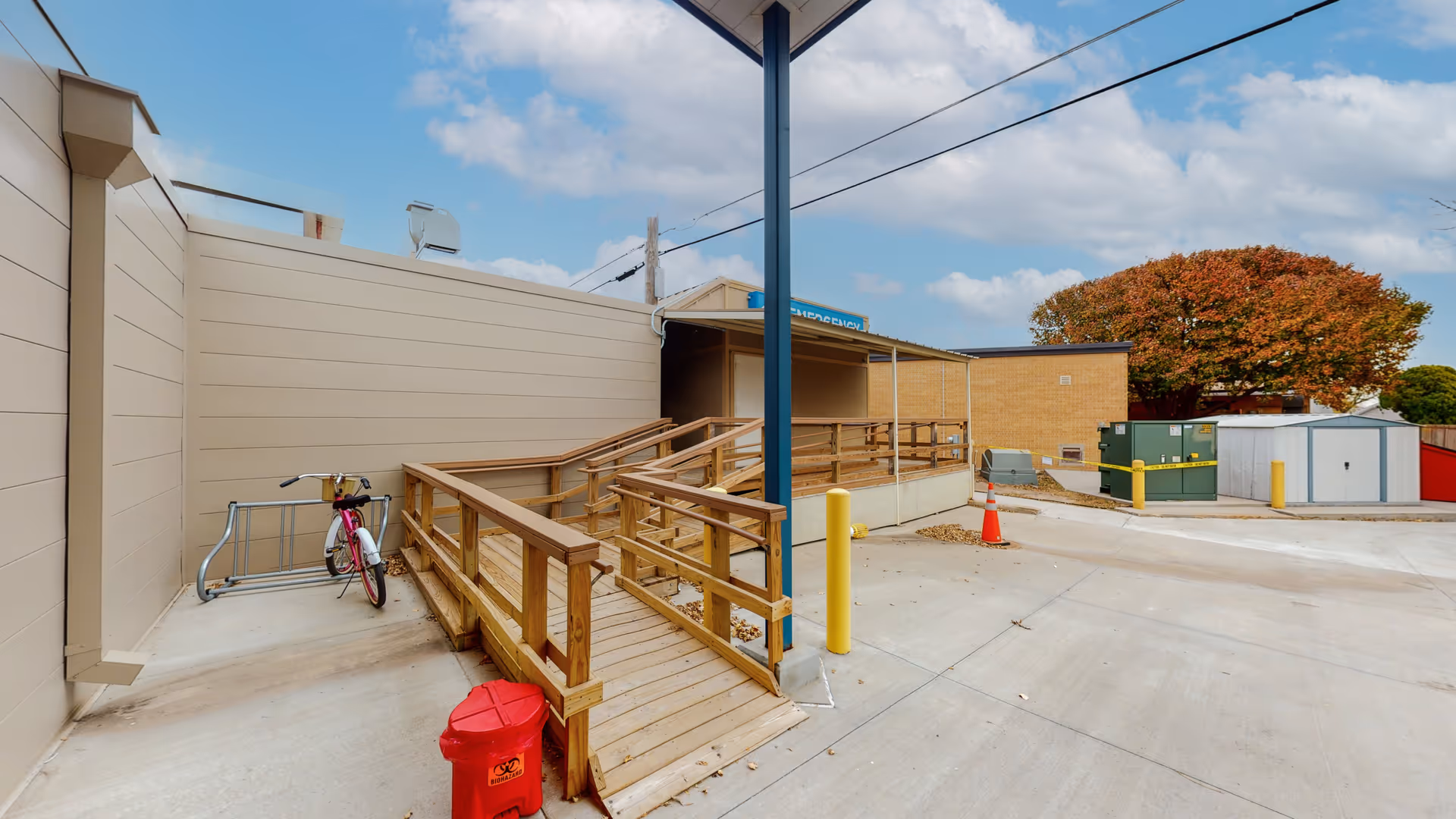Exterior view of a facility with wooden ramp, bike, and loading area.