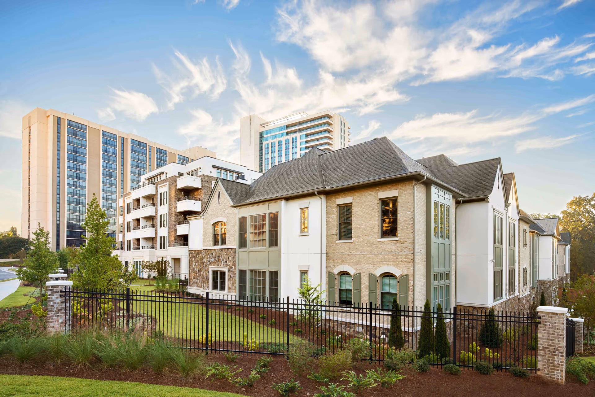 Exterior view of a modern senior living campus with brick, glass, and fencing.