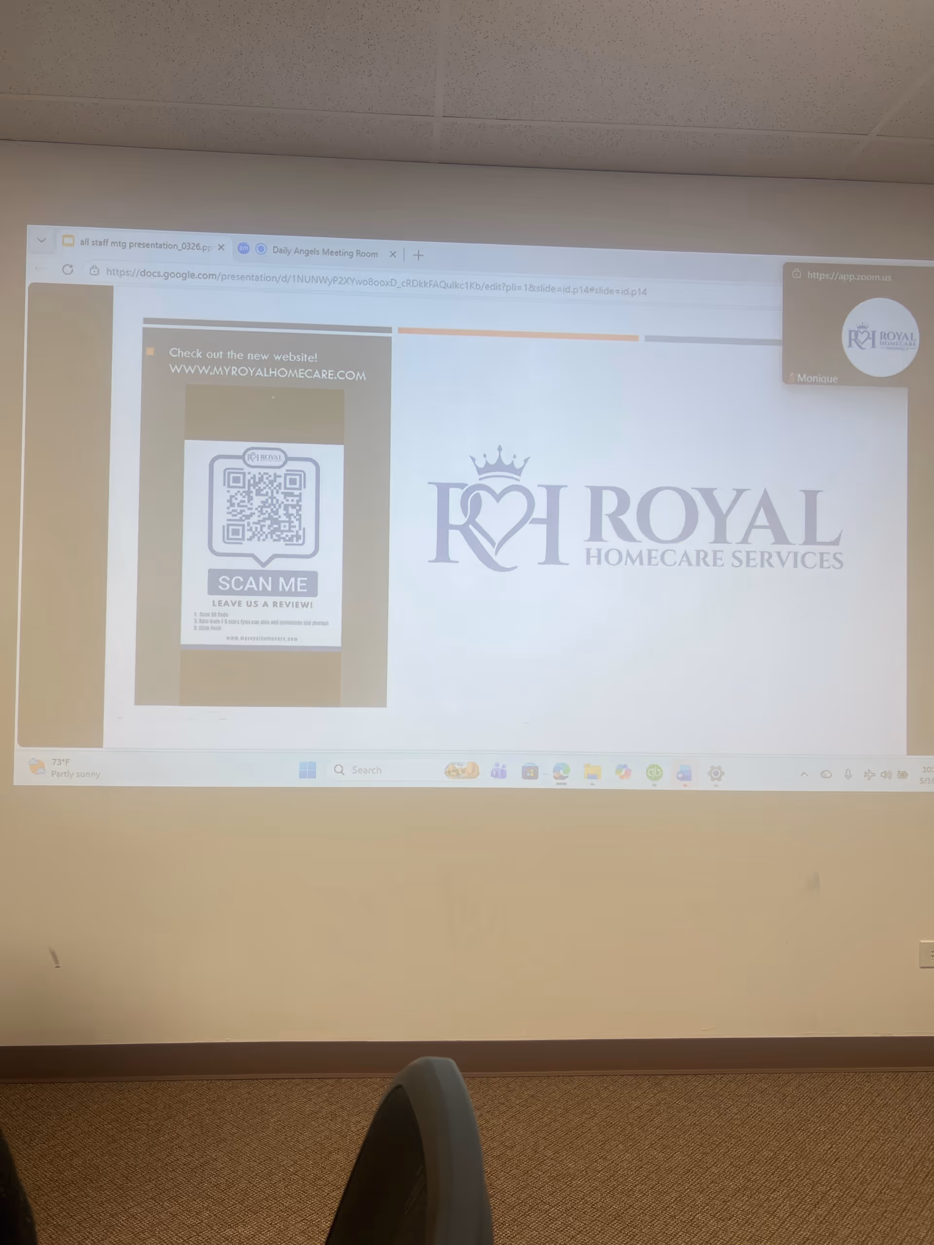 Projected slide on wall in a conference room shows Royal Homecare Services logo and QR code.