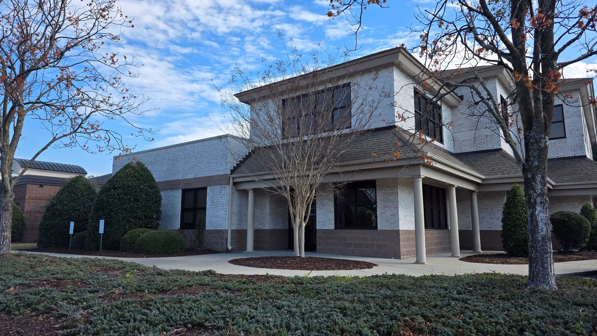 Exterior view of SILVERcare senior living facility with entrance and surrounding landscaping.