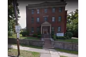 Brick Harrison House senior living facility with steps, entrance, and surrounding greenery.